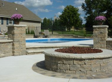 stone fire pit next to inground swimming pool