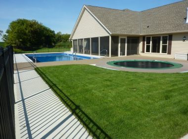 house with inground pool and trampoline in backyard